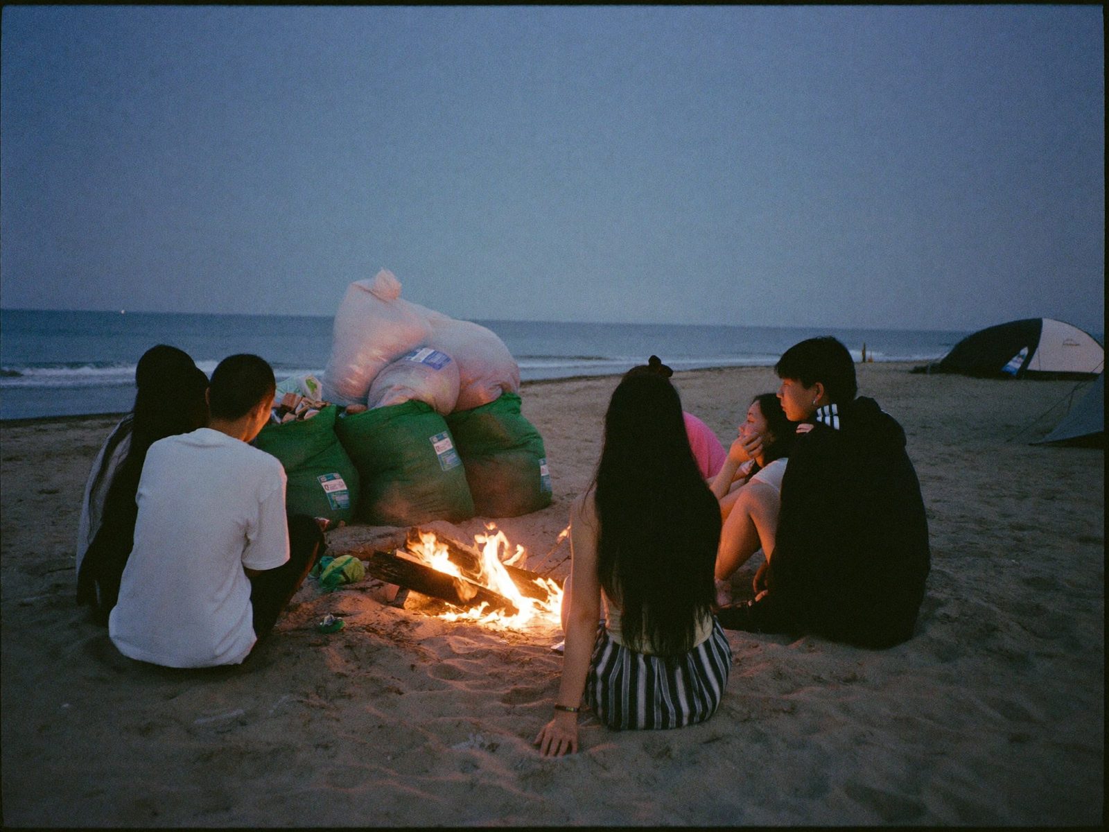 해변 정화를 마치고 모닥불에 둘러앉은 사람들